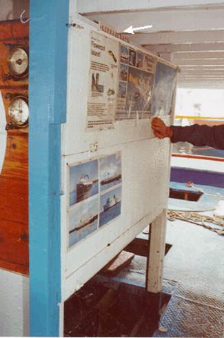 Photo 12 - Lifejacket locker in engine casing with door in closed position showing LIFEJACKETS sign (arrow) and posters on door